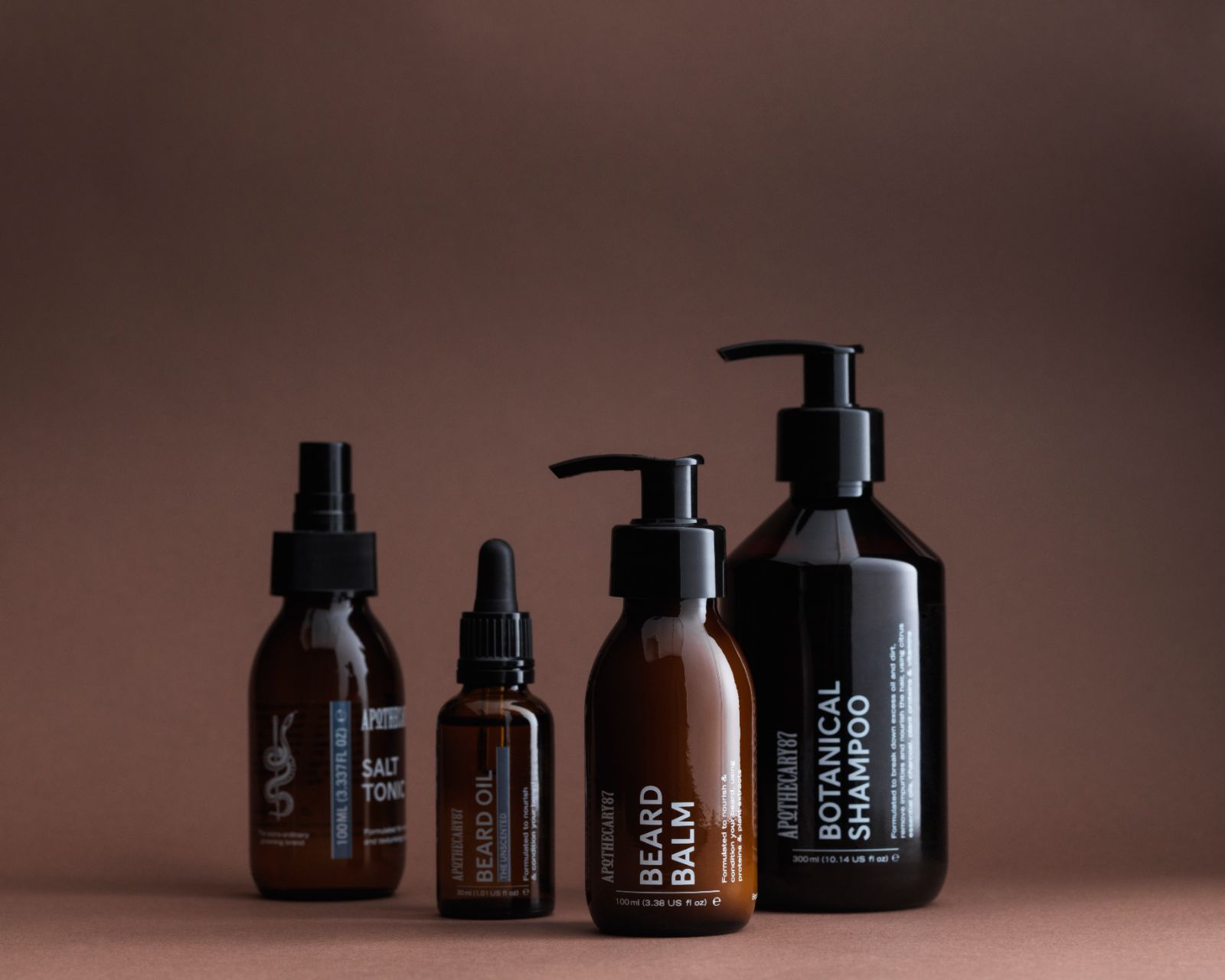 4 brown glass bottles of Apothecary 87 grooming products - branding and packaging design by 93ft Design. 