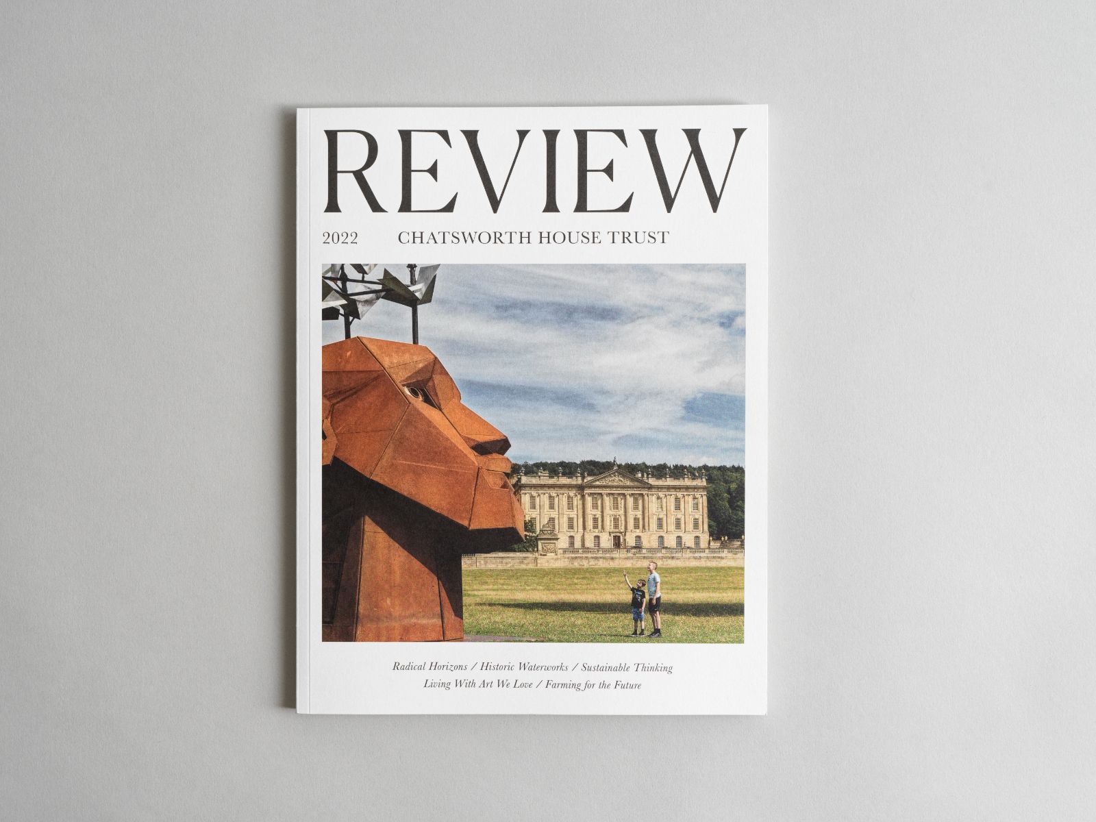 Flat lay of Chatsworth House Trust Annual Review. Front cover featuring a large iron head in front of Chatsworth House. 