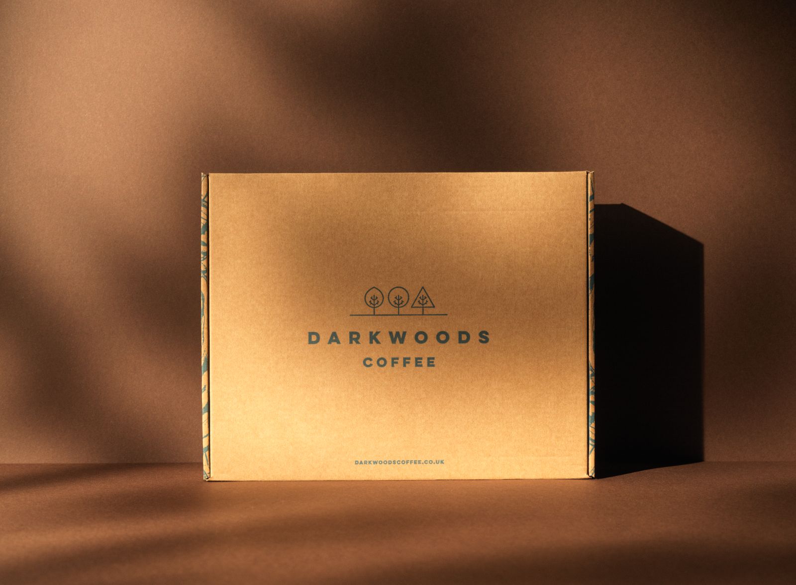 Dark woods coffee packaging design by 93. Brown cardboard mailing box with Dark woods branding and three trees logo design.