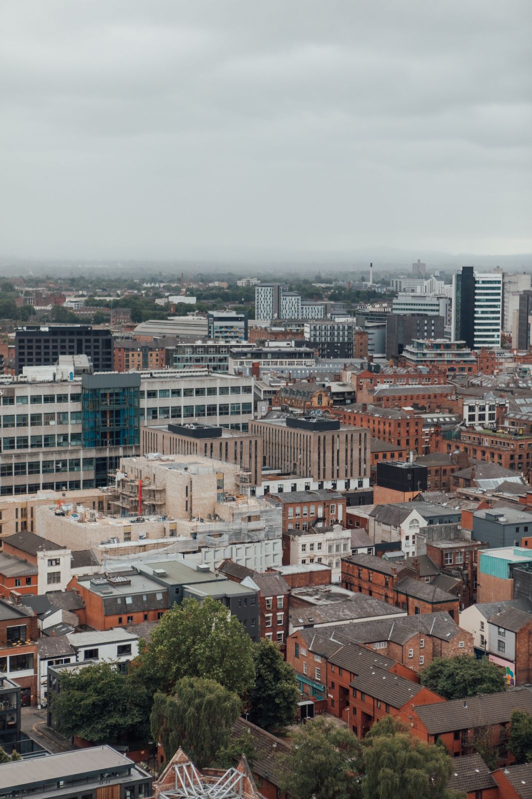 View from Swan Street House over Manchester, red brick buildings and trees. Soft grey daytime lighting.