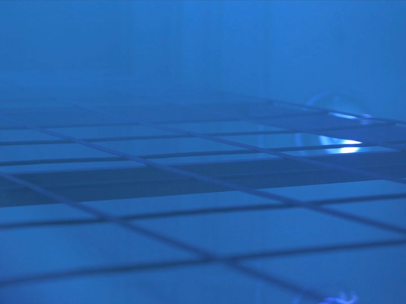 Close up of metal grid inside the Parla Physical Vapour Deposition machine - blue lighting.