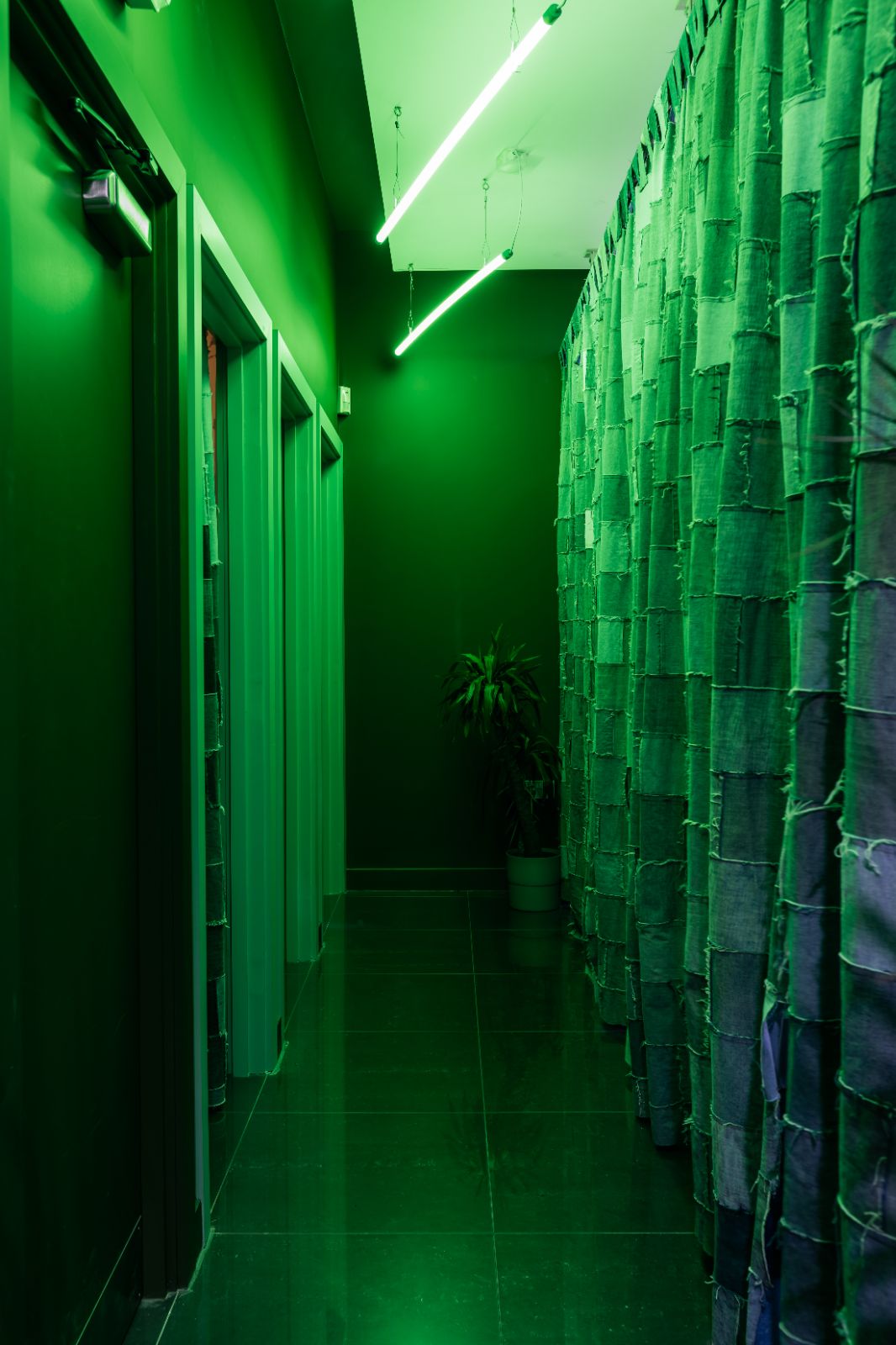 Shop dressing rooms with upcycled patched-denim curtains and two L.E.D tube lights tinting the space green