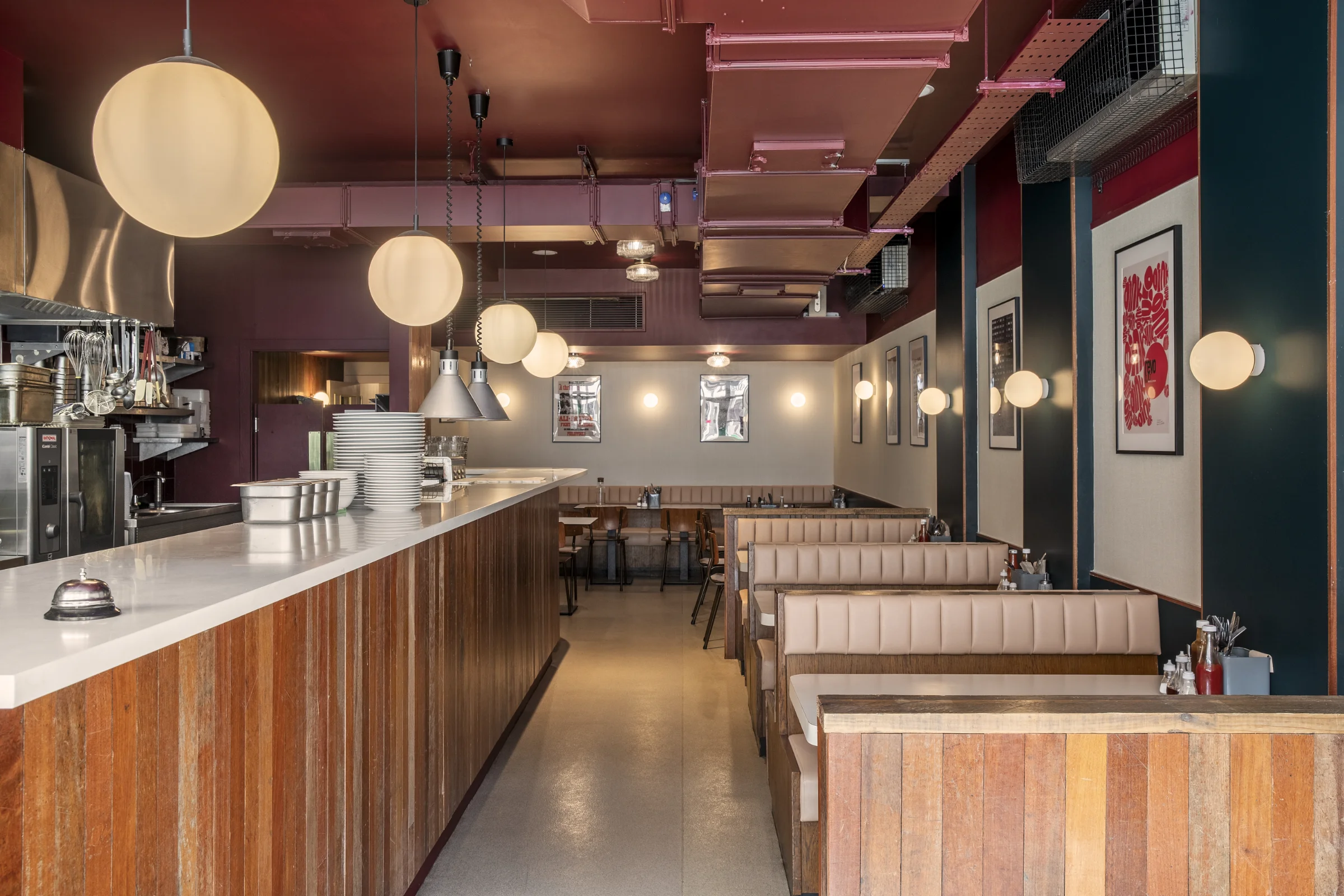 Le Swine interior image. Wood cladding, stone countertop, vinyl banquette seating, circular lighting, deep red and slate grey colours.