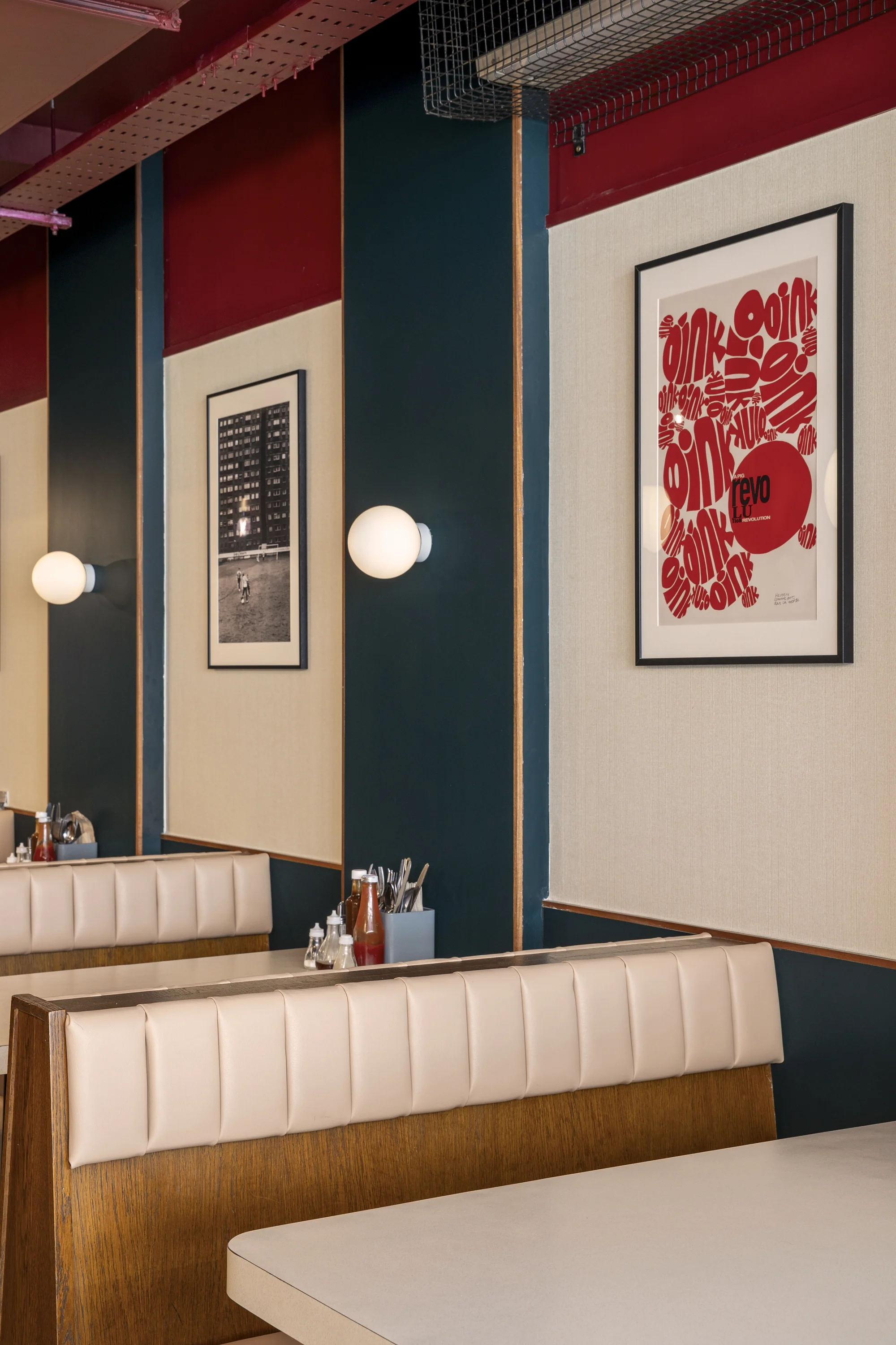 Banquette seating/booth. Artwork and prints on the wall, sauces and cutlery holders on tables. 