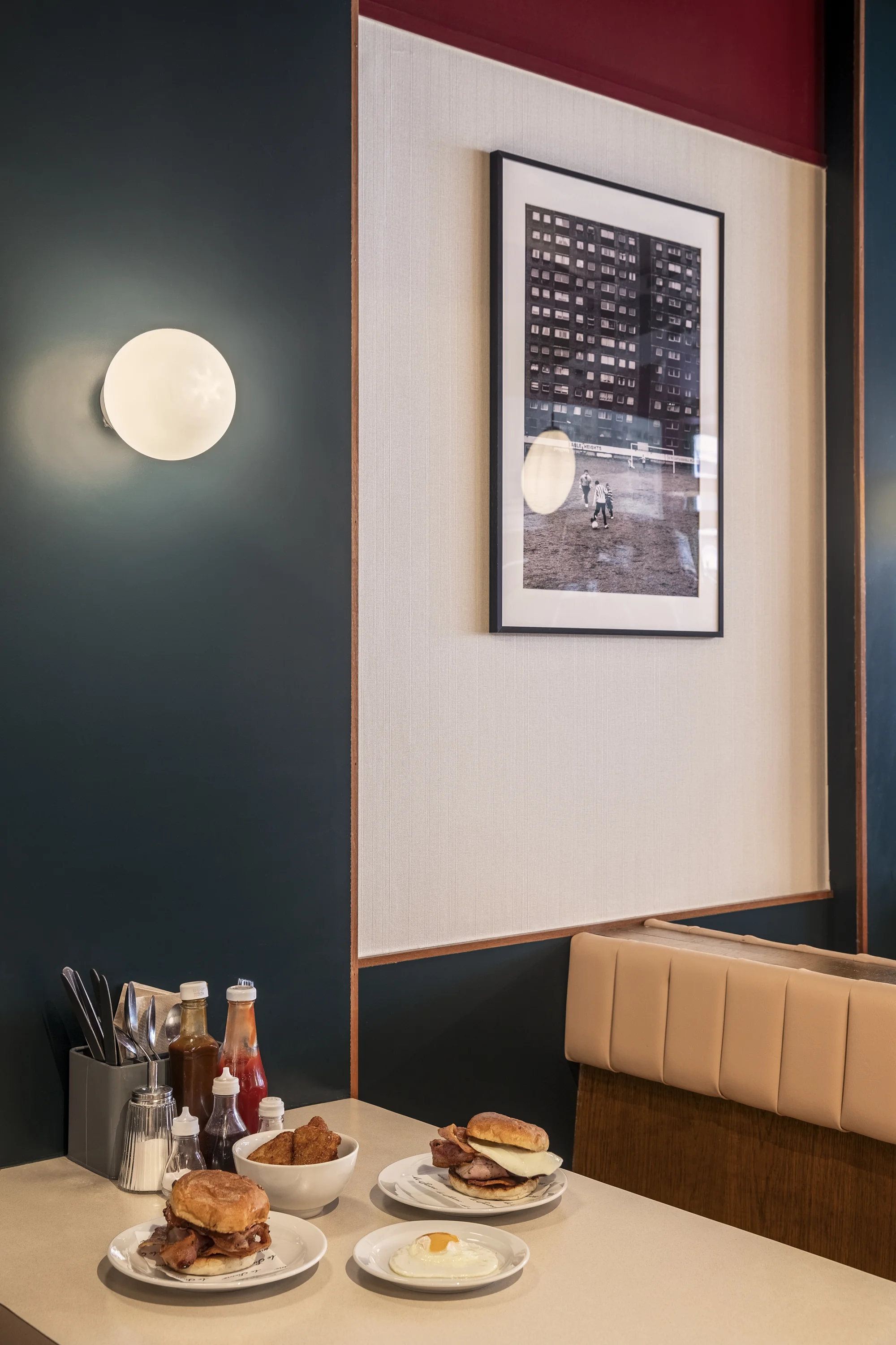 Seating arrangement. Traditional British fry-up cafe food placed on table with sauces and cutlery.