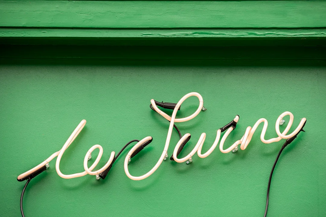 Custom Le Swine neon signage on painted green facade.