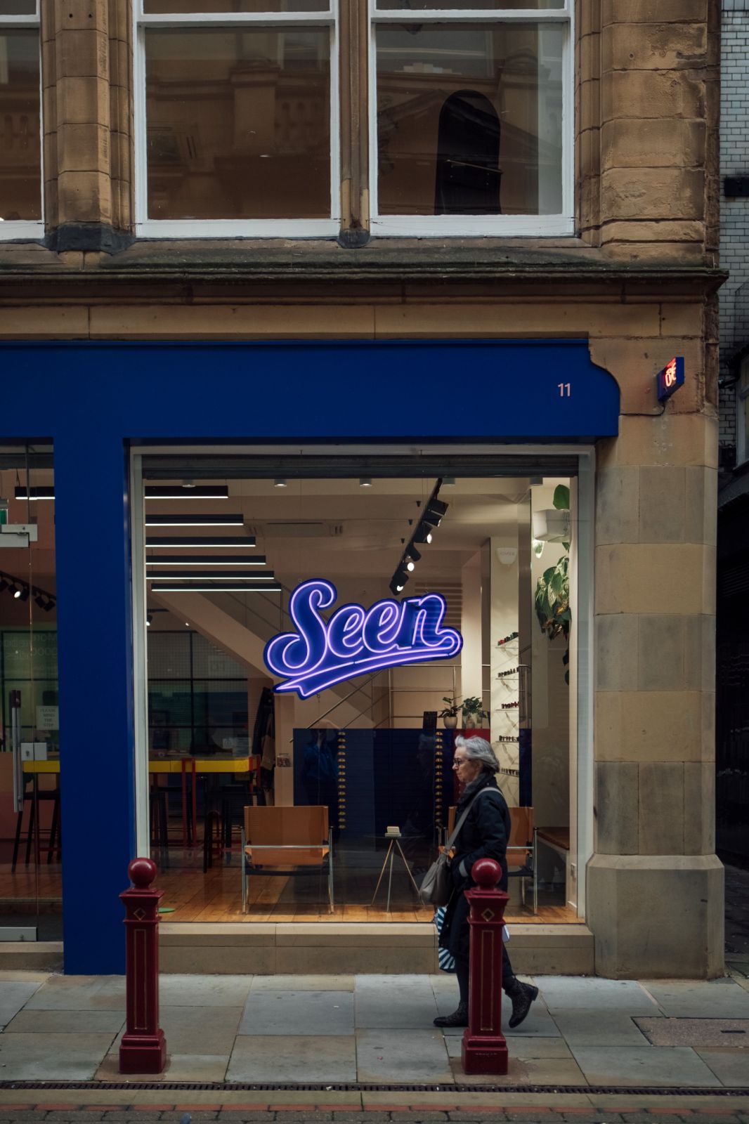 Manchester optician shop front with blue facia, large glass window and blue neon sign of the word Seen