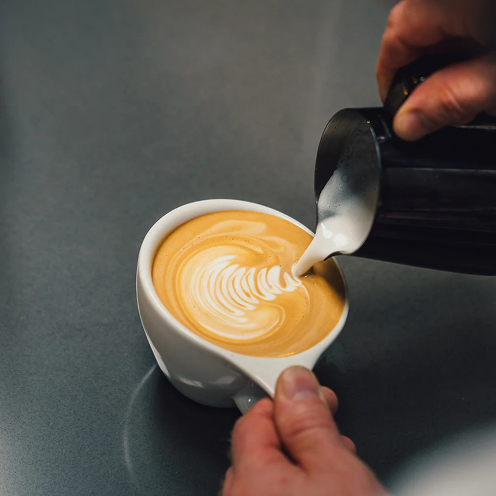 Pouring milk into coffee cup detail 