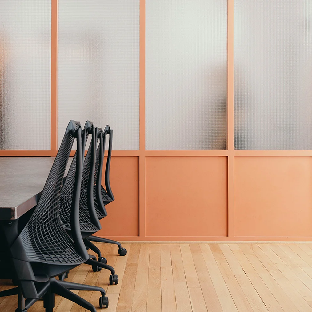 Interior detail, desk, chairs and partition wall with textured glass