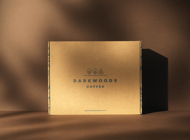 Dark woods coffee packaging design by 93. Brown cardboard mailing box with Dark woods branding and three trees logo design.