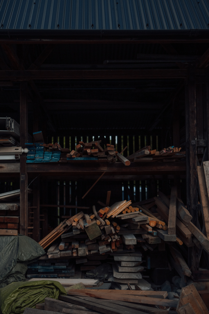 Covered woodstore with shelves and stacks of reclaimed planks and posts of varying colours.