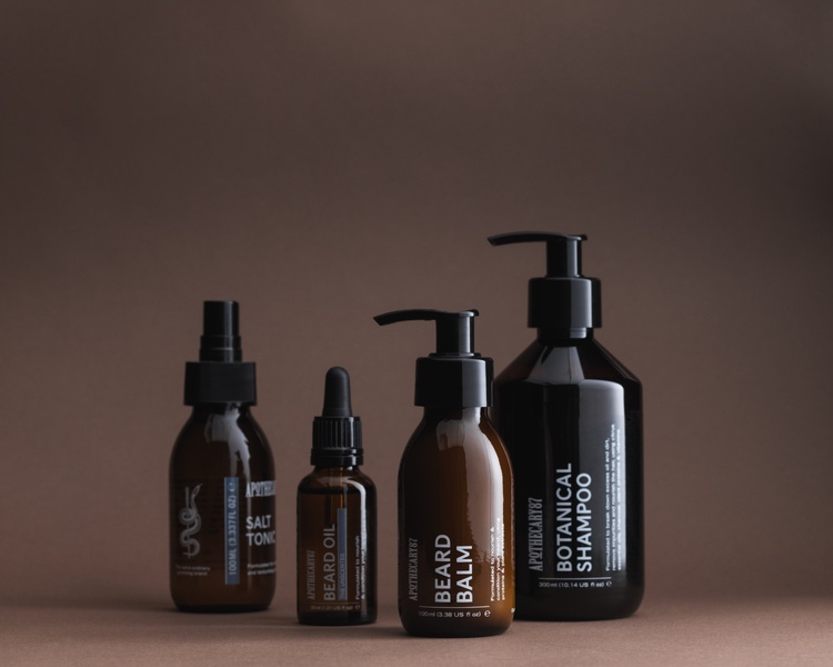 4 brown glass bottles of Apothecary 87 grooming products - branding and packaging design by 93ft Design.