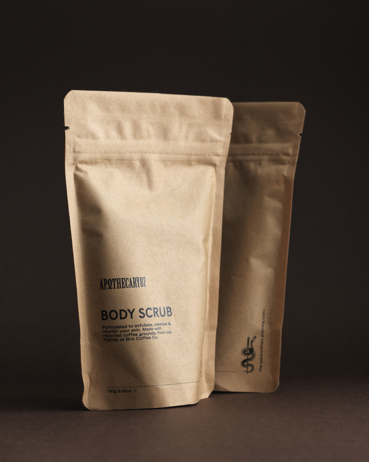 Two brown kraft paper packets of Apothecary 87 Body Scrub - branding and packaging design by 93ft Design. 
