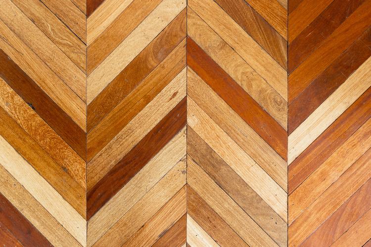 Reclaimed wooden floorboards of varying warm brown and tan shades and laid in a chevron design