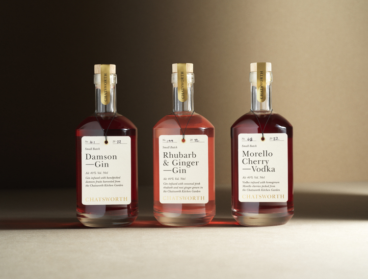 Warmly-lit, beige backdrop. 3 Chatsworth drinks bottles with pink liquid: DAMSON GIN, RHUBARB GIN, MORELLO CHERRY VODKA. 