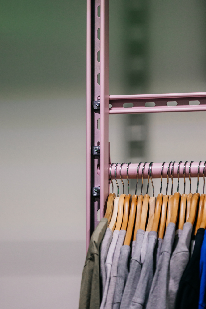 Pink powder-coated unistrut shelving system as railing hanging t-shirts for vintage clothing store in Sheffield